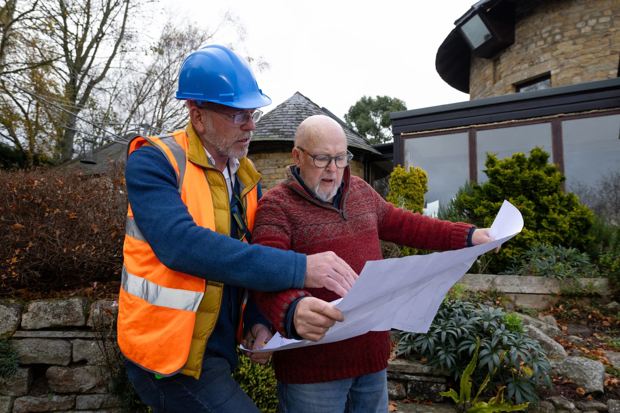 Construction professional reviewing plans with a client on site