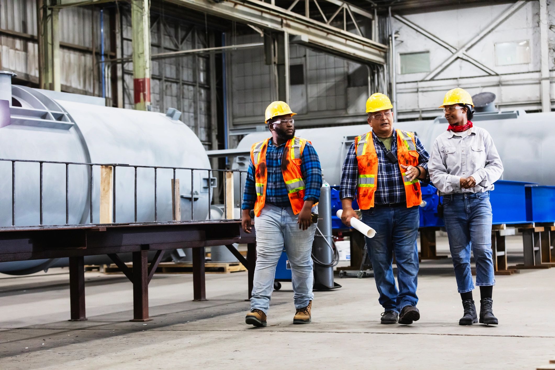 Workers walking through a steel fabrication facility discussing plans