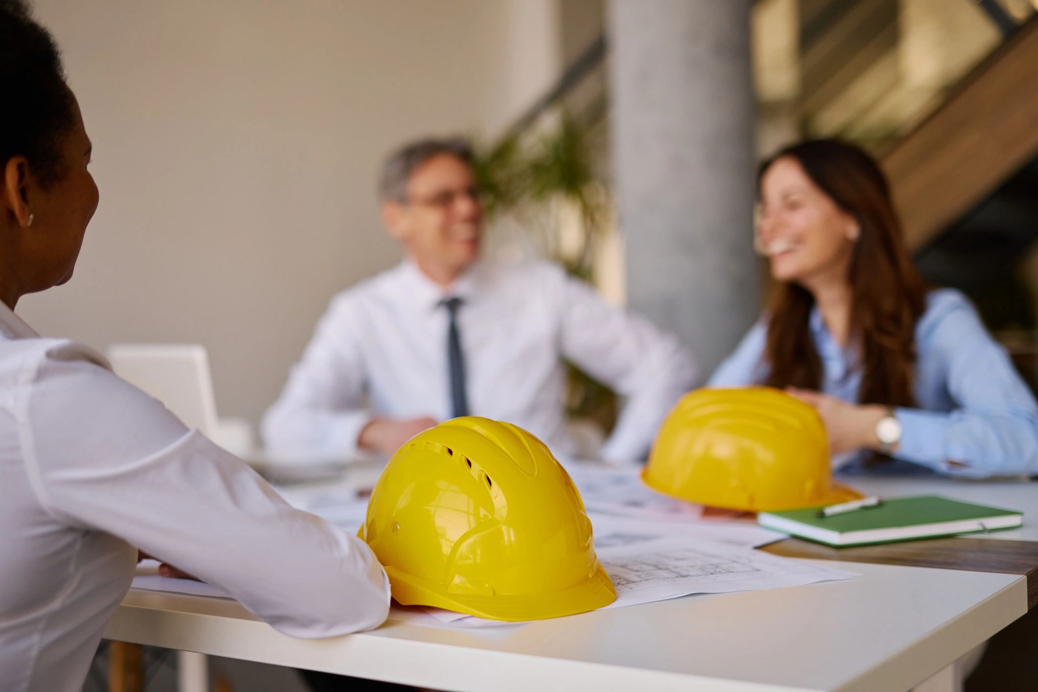 Architects discussing a construction project with hard hats on the table